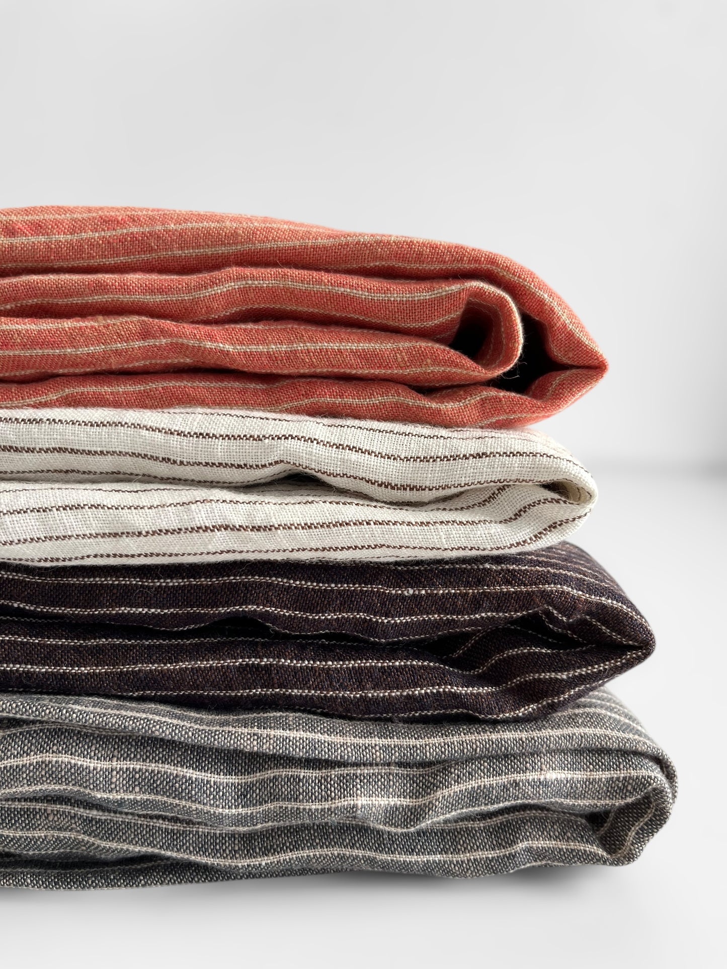 Stack of folded striped fabric in various colors on a light background