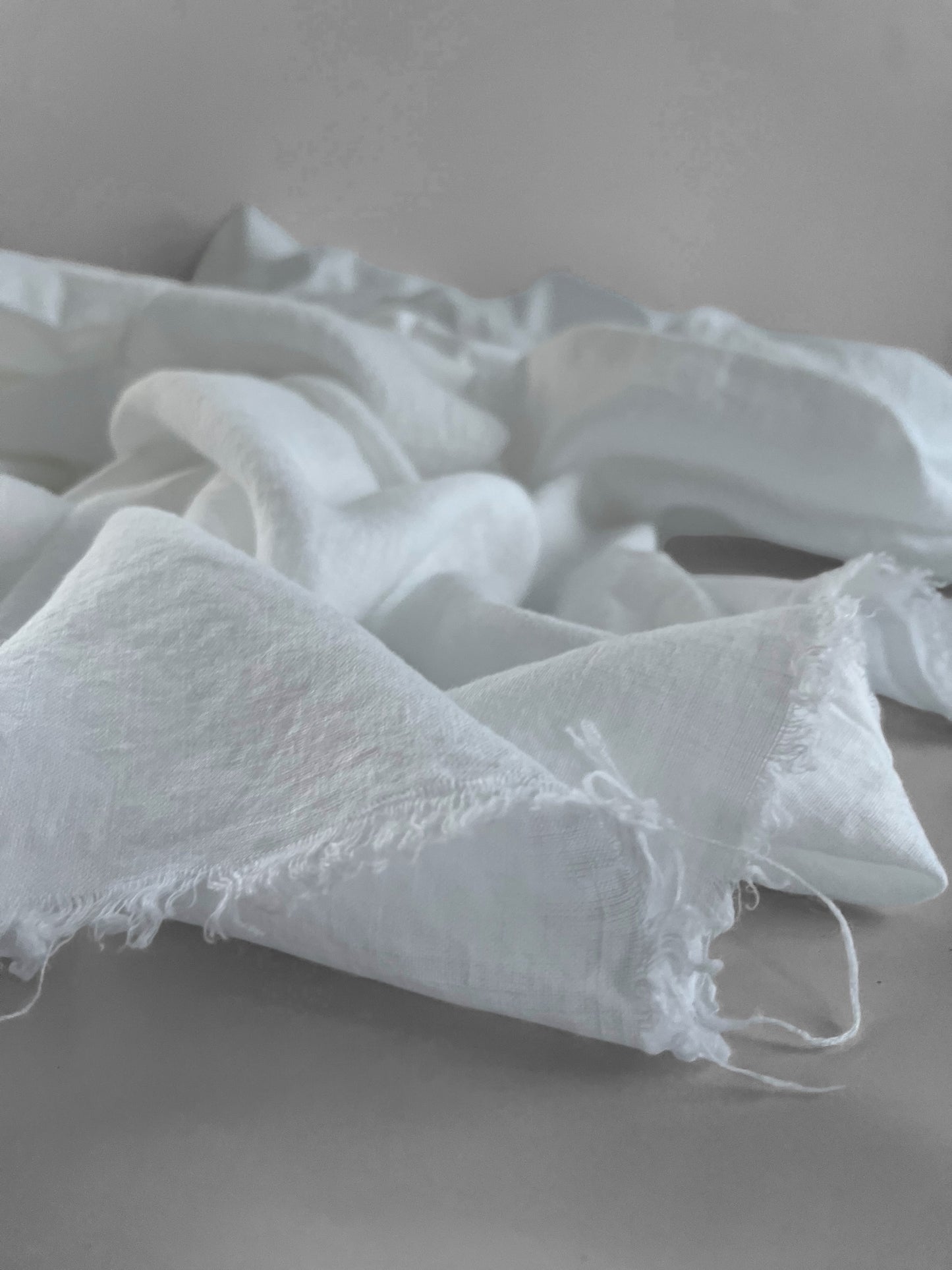White linen fabric with frayed edges on a gray surface