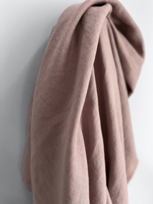 Folded pink linen fabric on a light gray background