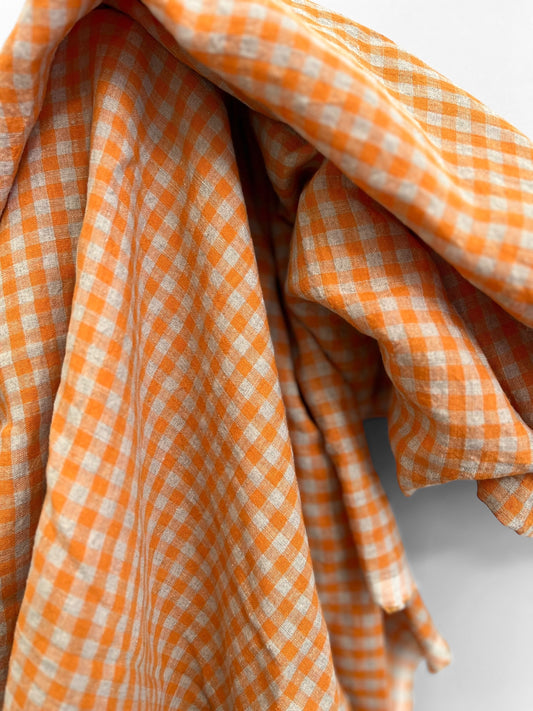 Close-up of orange and white checkered fabric on a light gray background