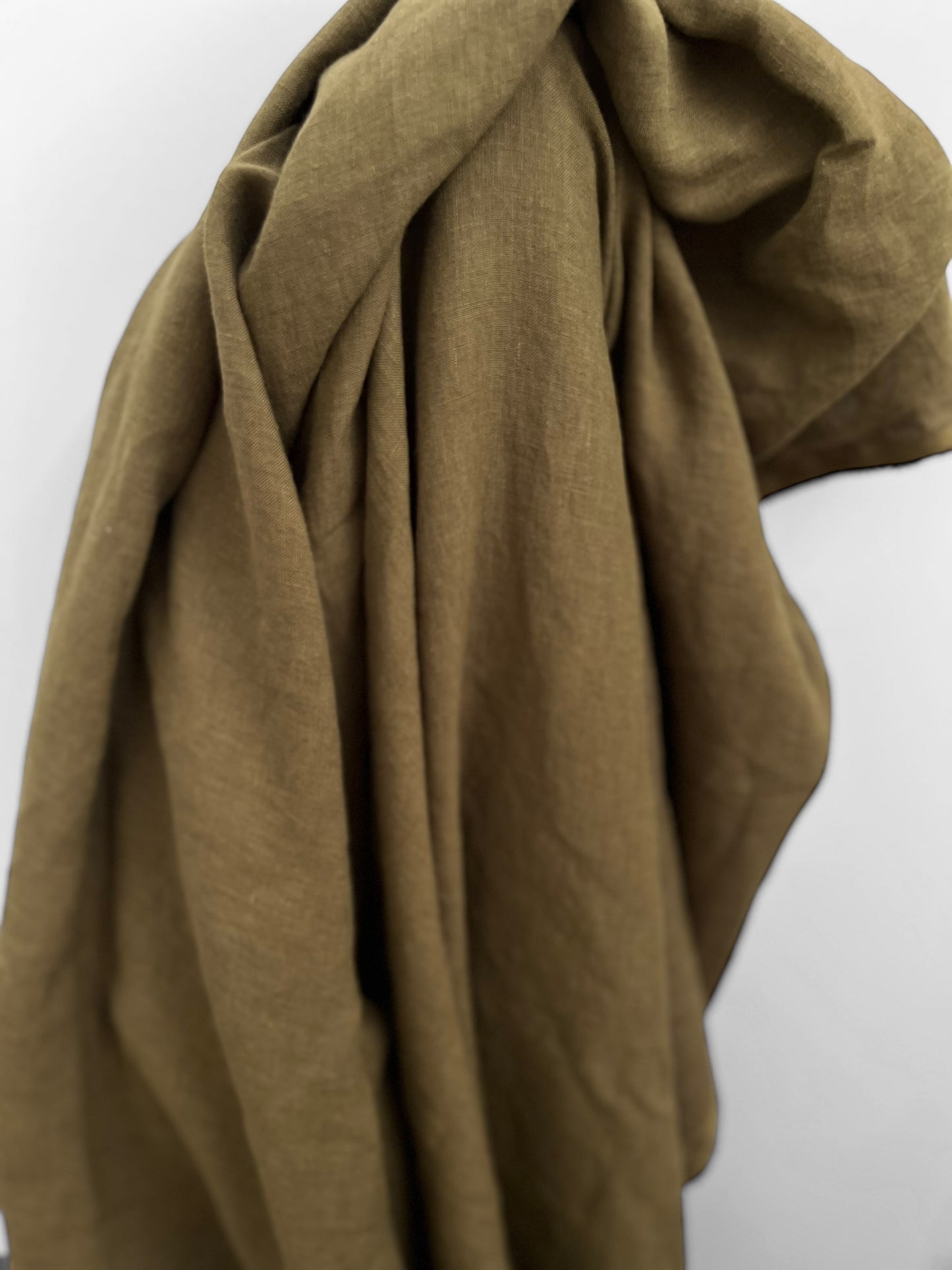 Khaki green linen fabric draped over a white background