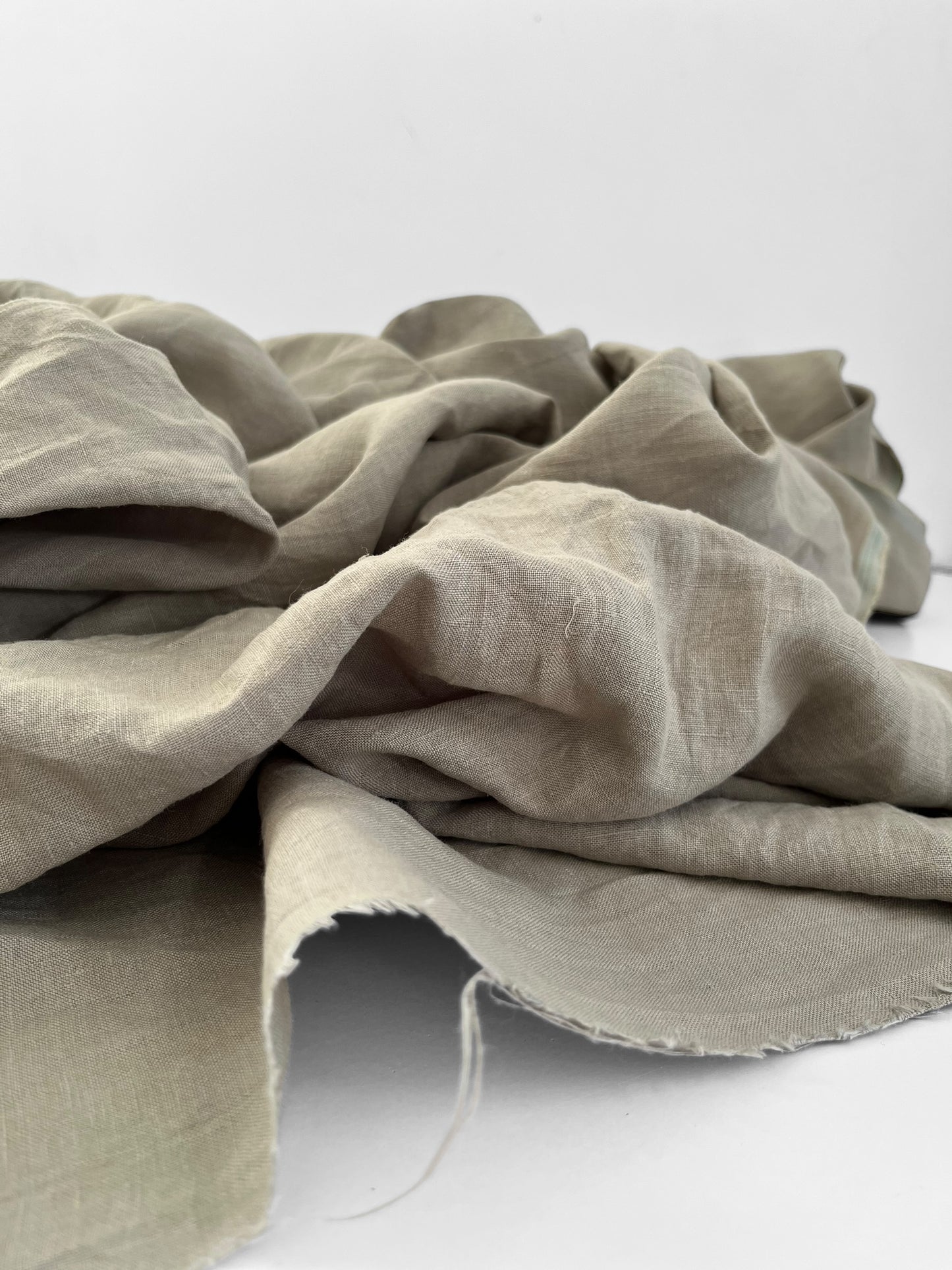 Sage green linen fabric draped over a white surface