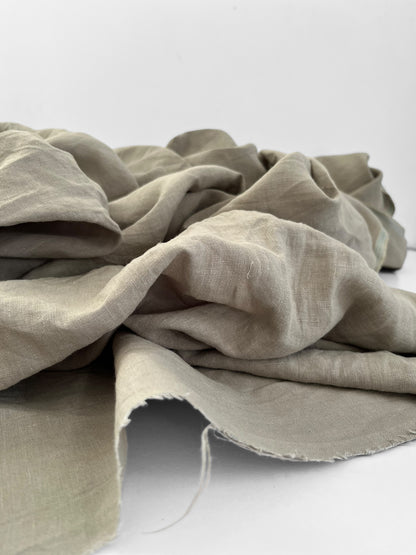 Sage green linen fabric draped over a white surface