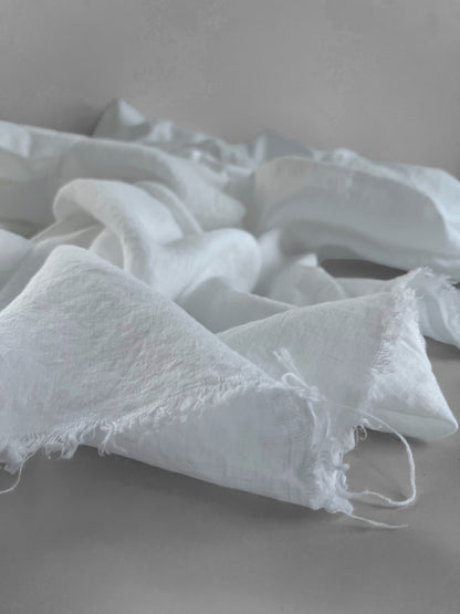 White linen fabric with frayed edges on a gray surface