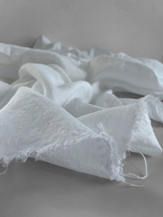 White linen fabric with frayed edges on a gray surface
