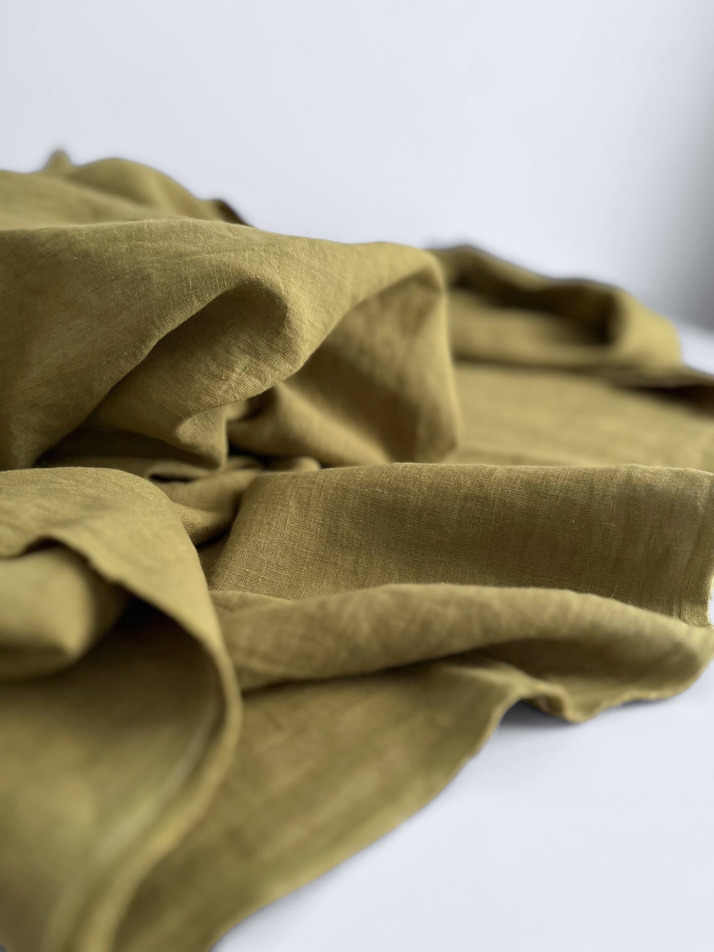 Folded green linen fabric on a white background