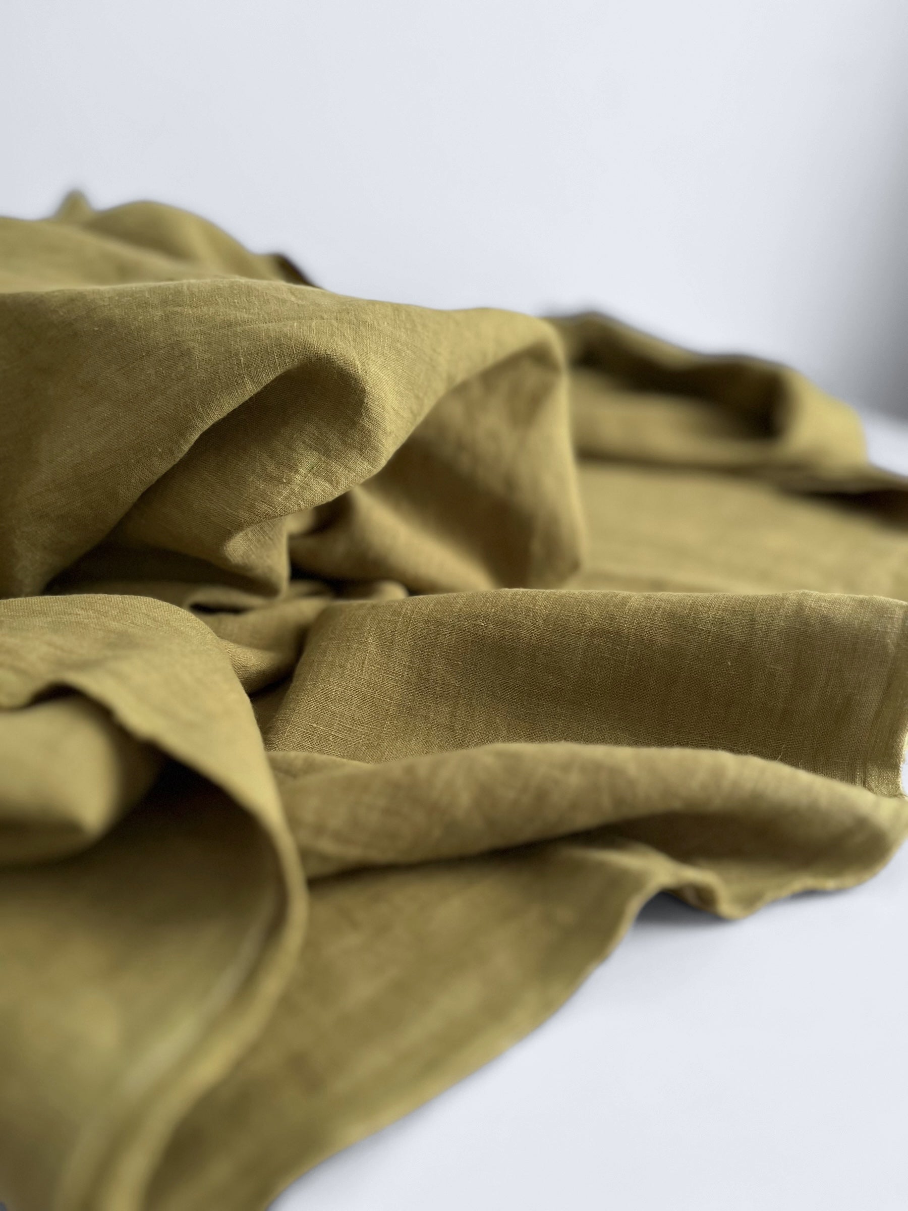 Folded green linen fabric on a white background